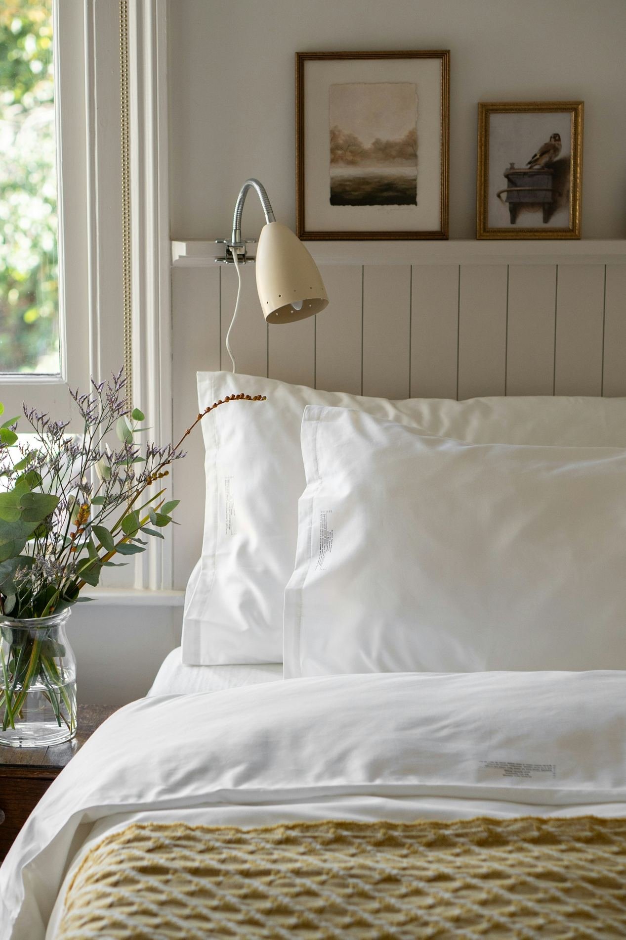 A made bed with white linen and pillows