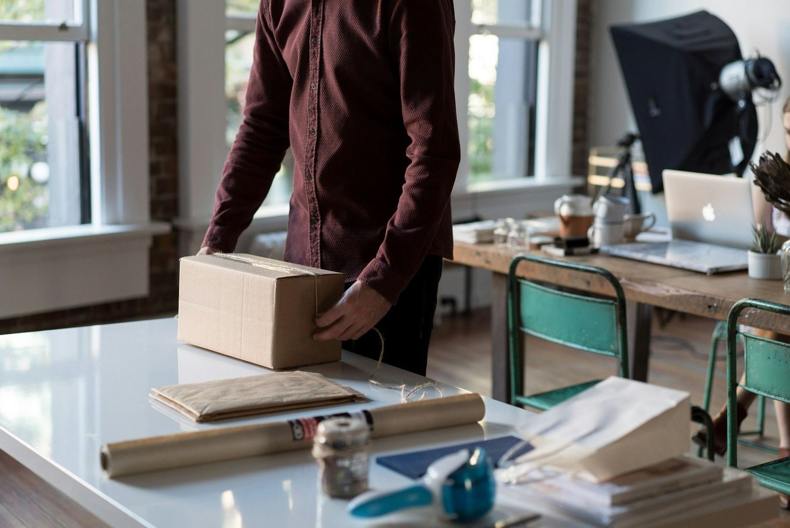 A person packing an order into a cardboard box at a work table