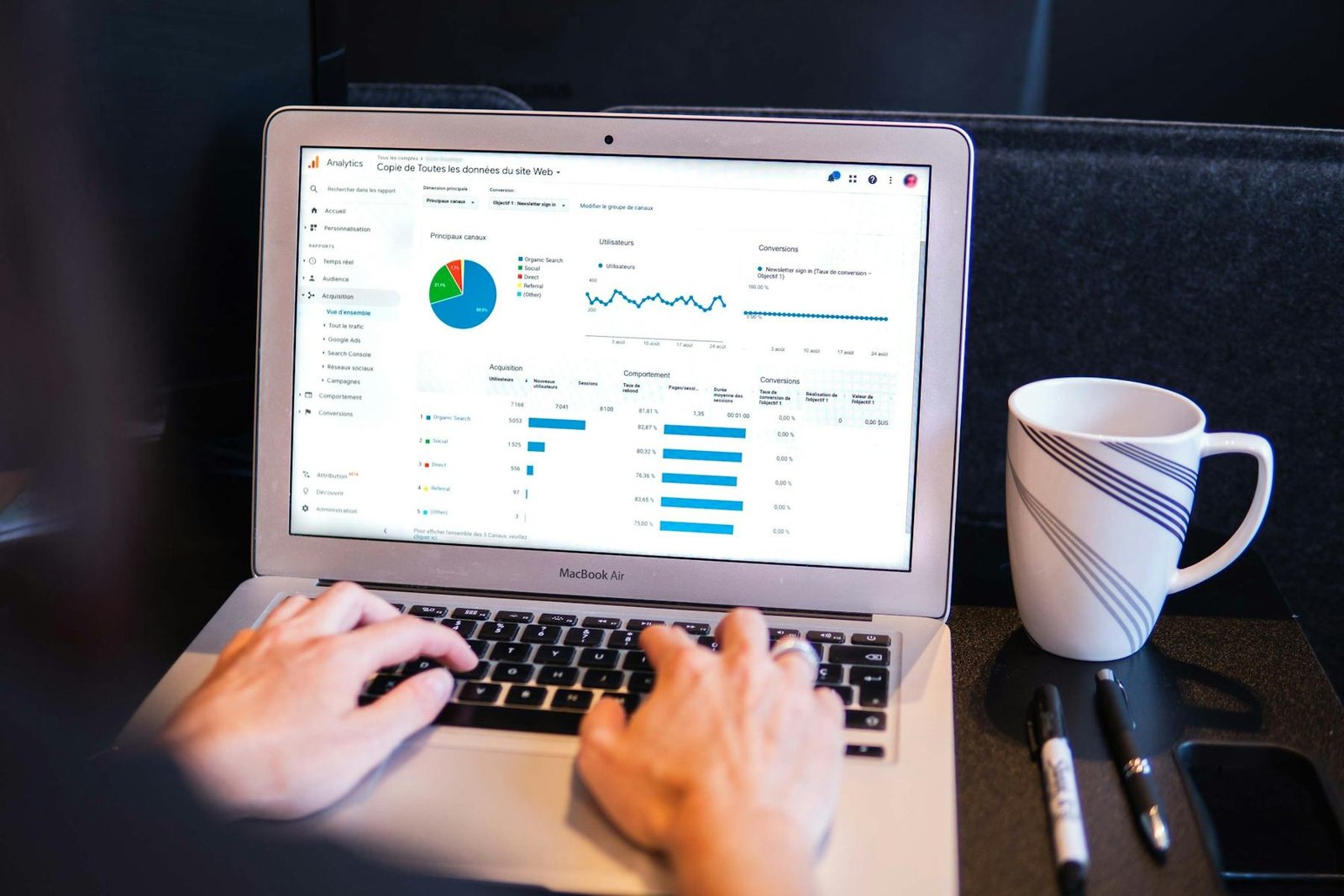 Hands on a laptop showing a web page with charts